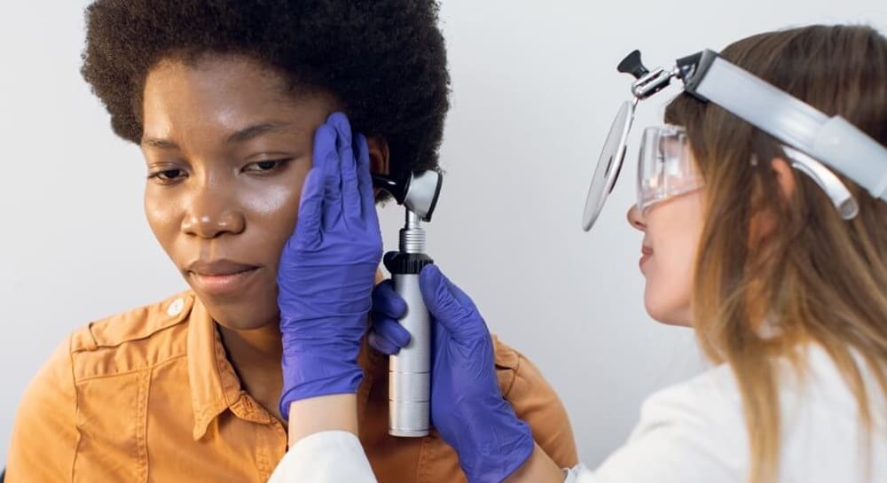 Specialist ENT consultant examining patient ear with an otoscope